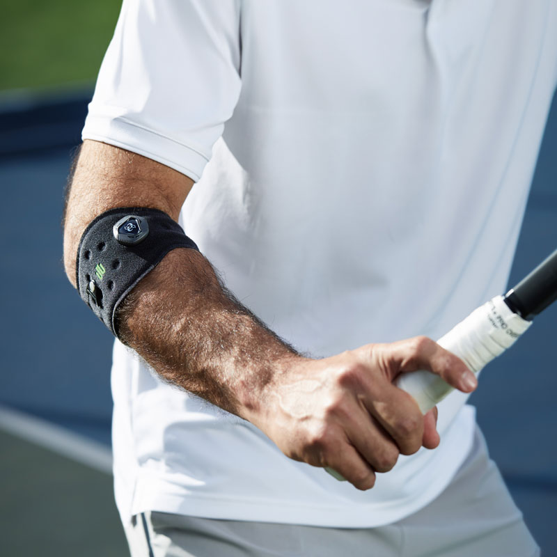 Onderarm van een tennisspeler op de elleboog, een verband dat het racket in de hand houdt
