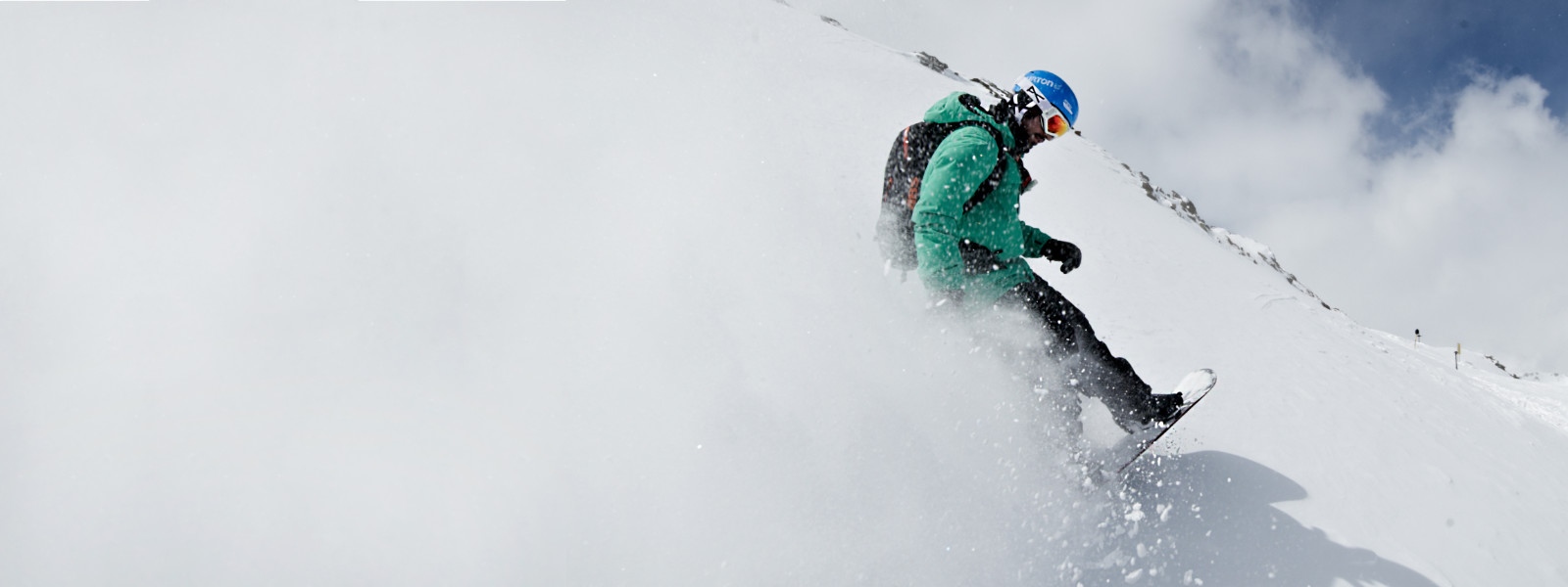Snowboarduitrusting voor nog meer swing - hier bij ons Snowboarders met een groene jas wervelt sneeuw waarop de hele linkerkant van de foto wit verven tijdens het remmen