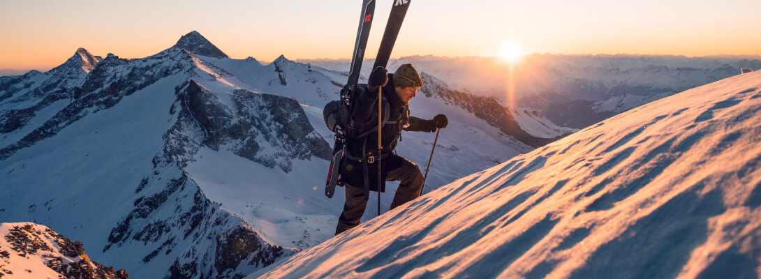Skitouringgänger am Berg Skitouring Gänger erklimmt mit seinen Touringski auf dem Rücken den Berg