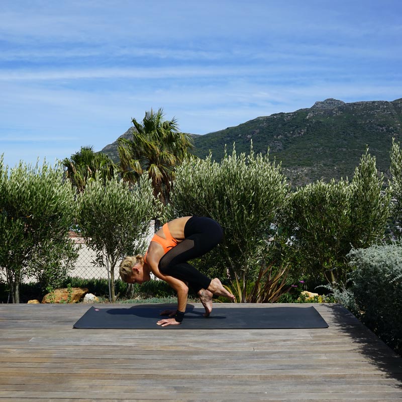 Vrouw maakt yoga in balans op haar terras op haar handen, terwijl haar benen zichzelf langzaam in de lucht tillen