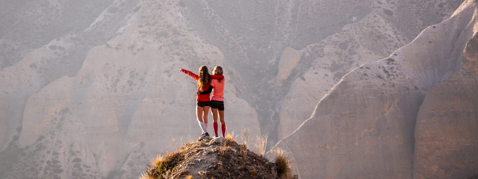 Twee vrouwen juichen een bergtop toe