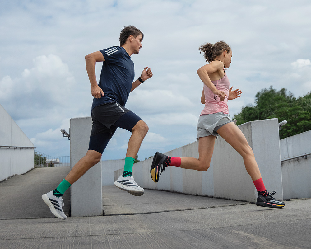 Twee dunne lopers met witte en roze lopende sokken lopen enigszins schuine stenen stappen omhoog
