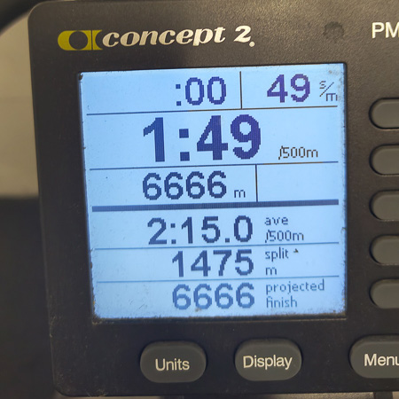 6666 meter op de SkiErg – zweet liegt niet! Close-up van een SkiErg-trainingsmonitor. Het scherm toont een afstand van 6666 meter, een gemiddelde tijd van 2:15 per 500 meter en een tijd van 1:49 per 500 meter.