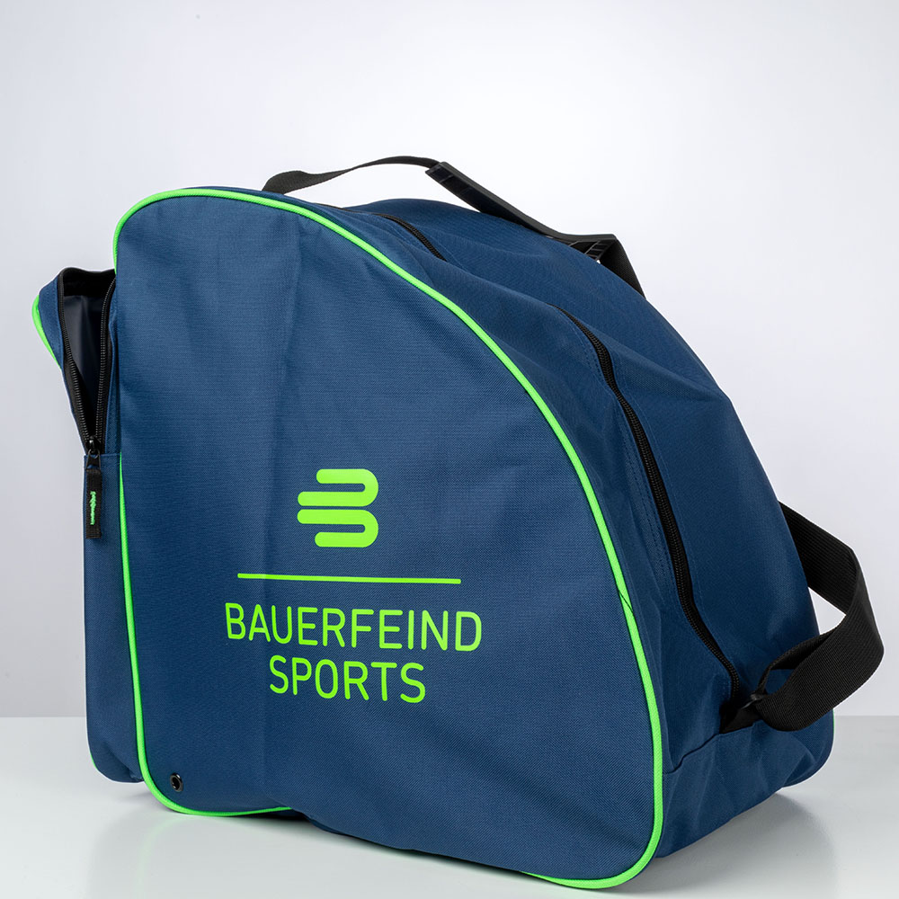 Bauerfeind Sports Skitas Buiten De Bauerfeind Sports skitas staat buiten op een houten bank. De tas is blauw met een groene rand en heeft een zwarte draagriem. De bomen op de achtergrond suggereren een buitenomgeving.