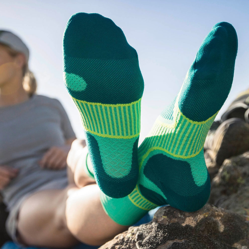 Wanderin legt haar benen op tijdens een pauze	 focus op de groene wandelende sokken die ze draagt
