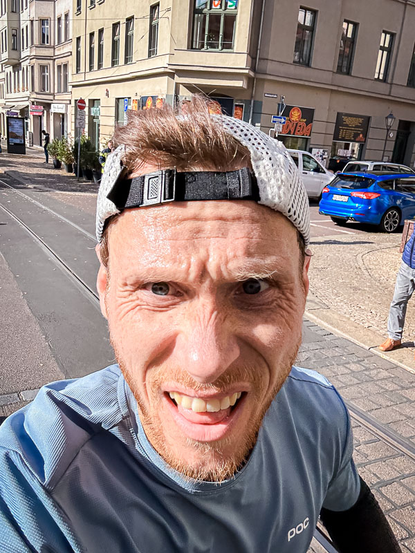 Strijdend door de laatste kilometers van de halve marathon – Vastberadenheid ondanks gemiste persoonlijke beste tijd Een uitgeputte loper ploetert door de laatste kilometers van een halve marathon. Ondanks vermoeidheid zet hij door om de race te voltooien, ook al lijkt een persoonlijk record onhaalbaar.