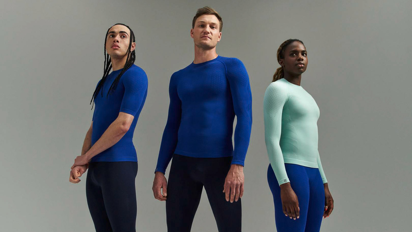 Drie atleten in sportkleding met compressieshirts en compressiebroeken Drie atleten in sportkleding met compressieshirts en compressiebroeken voor een grijze achtergrond.