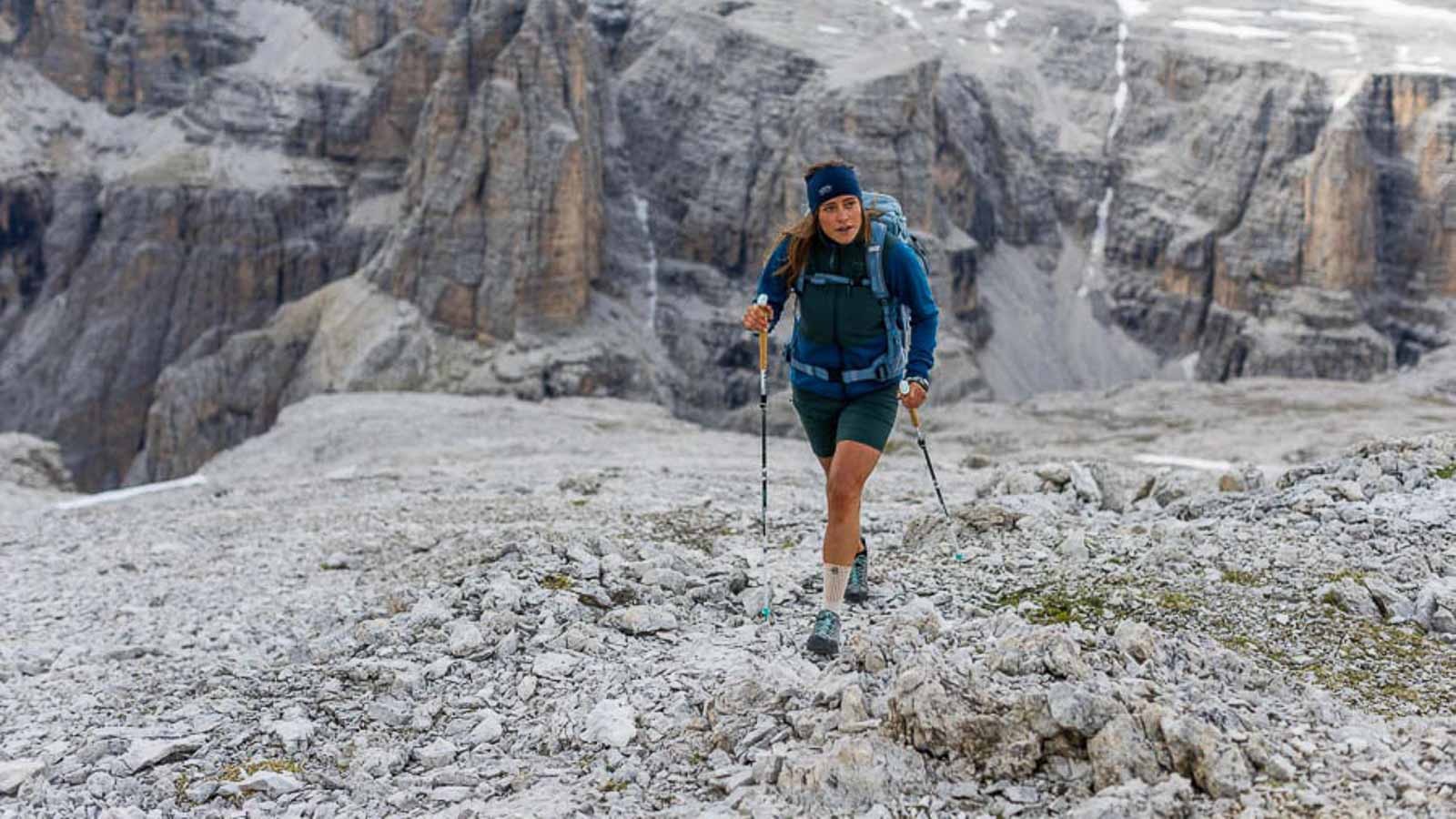 Een uitdagende maar prachtige wandeling in de Dolomieten Een wandelaar in de Dolomieten loopt met stokken over een steenveld en draagt een wandelbandage. Italienisch: Una escursion