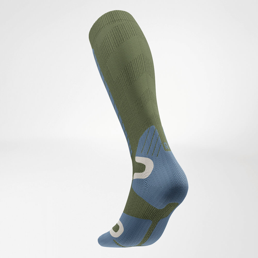 Schuine achteraanzicht van een groene kniehoge ski-compressiesok met gestructureerd breipatroon voor optimale ondersteuning en comfort tijdens het skiën.