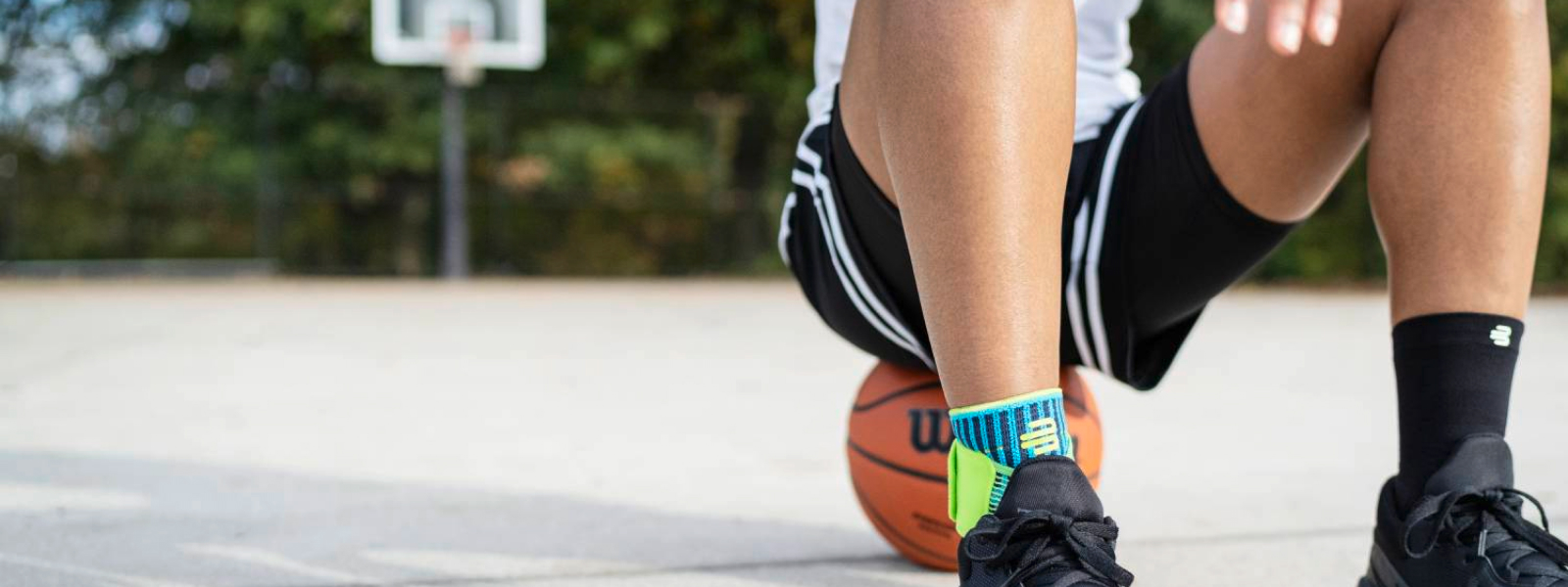 Streetballspeler met voetbinding staat op een basketbal op een straatveld