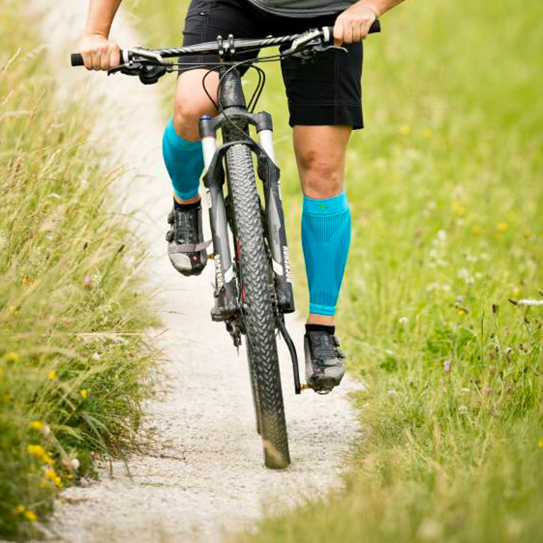 Frontale opname fietser draagt ​​waden-mouwen tijdens het rijden via een grindpad op de mountainbike