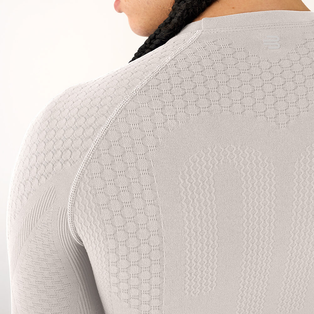 High-tech for your back – Our shirt stabilizes every move you make Close-up of a man's back wearing a beige compression shirt with a tight fit and varied knit zones for targeted support.