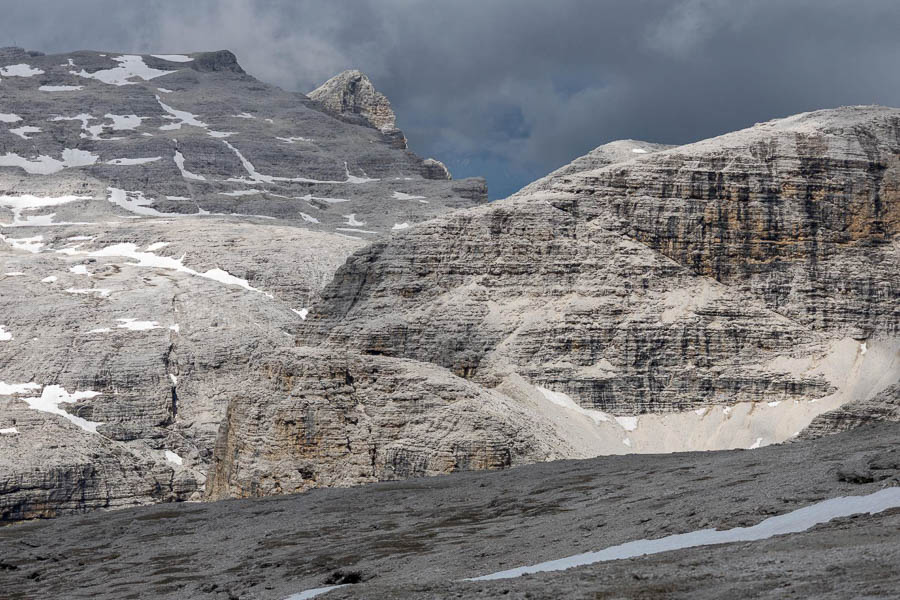 Rotsachtig landschap in de Dolomieten Een rotsachtig landschap in de Dolomieten met verspreide sneeuwplekken en een bewolkte hemel.