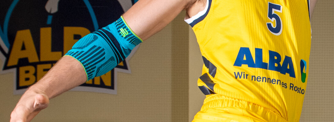 Basketbalspeler met Alba Berlin Jersey draagt ​​een sportverband voor de elleboog