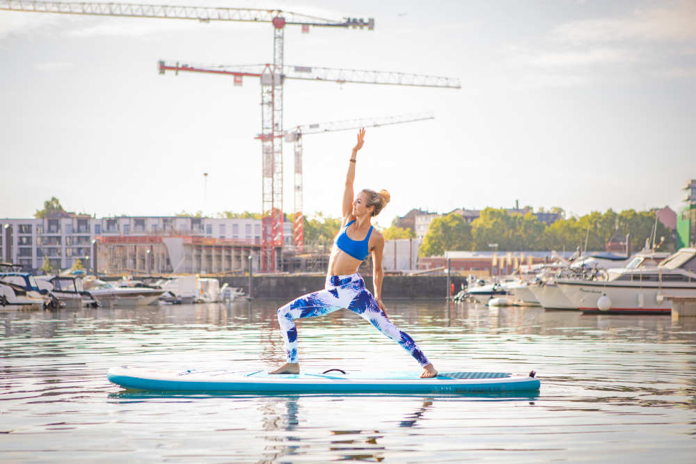 SUP YOGA - Spectaculair en efficiënt Vrouw maakt yoga op het water: op haar handen op haar handen staan