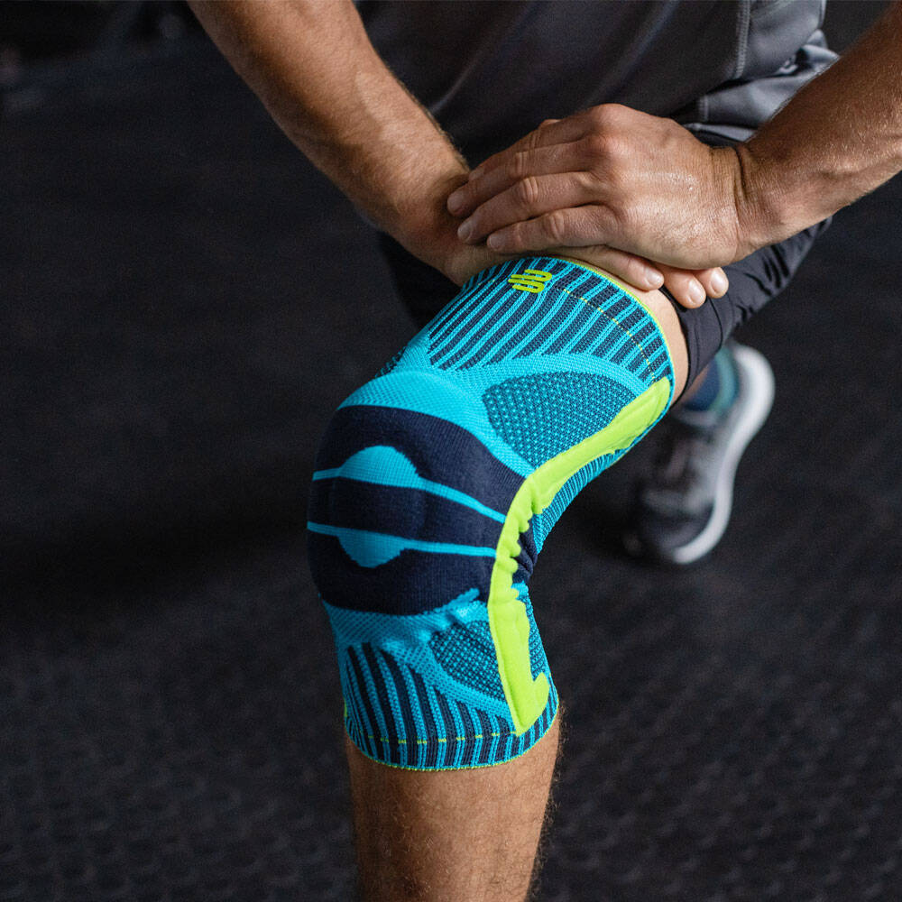 Sportknieondersteuning voor squats - Fitness Training Man buigt zijn knie en draagt een sportkniesteun