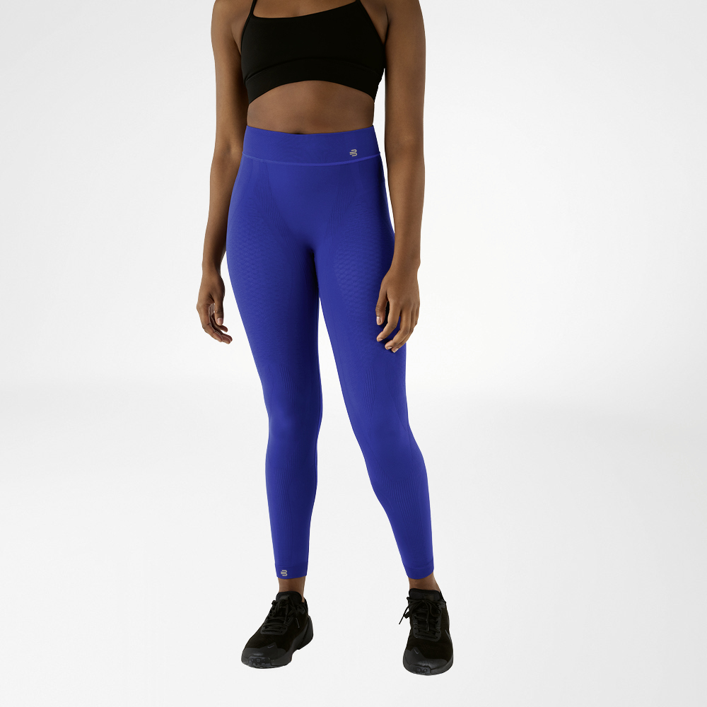 Een vrouw in een zwarte sportbeha en marineblauwe, enkellange sportbroek met hoge taille