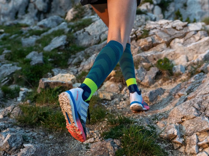 De hardloper loopt Stony bergafwaarts en draagt ​​trailrunsokken