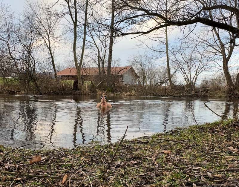 Anna Hahner mediterend in de rivier Anna Hahner bidt met gevouwen handen in de rivier, omringd door kale bomen.