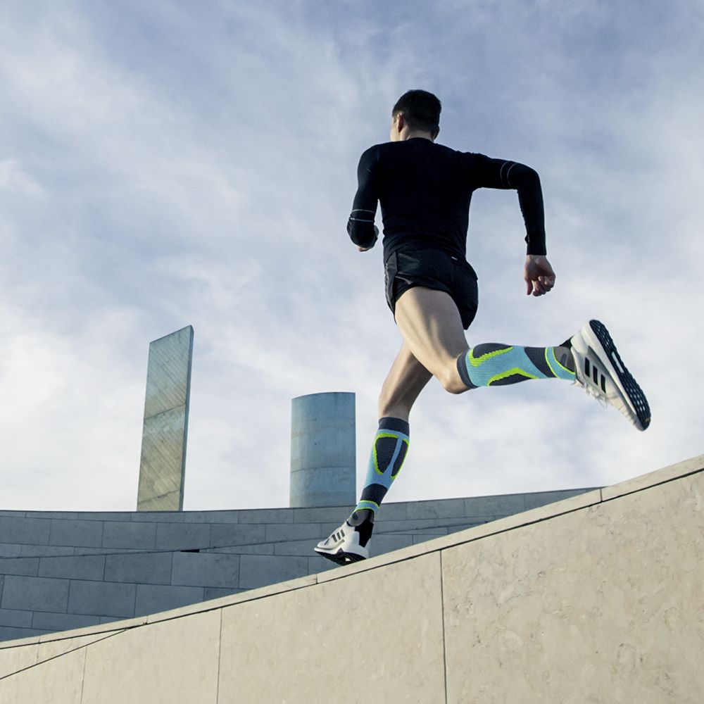 Runner met compressiesokken om op een stenen muur te rennen