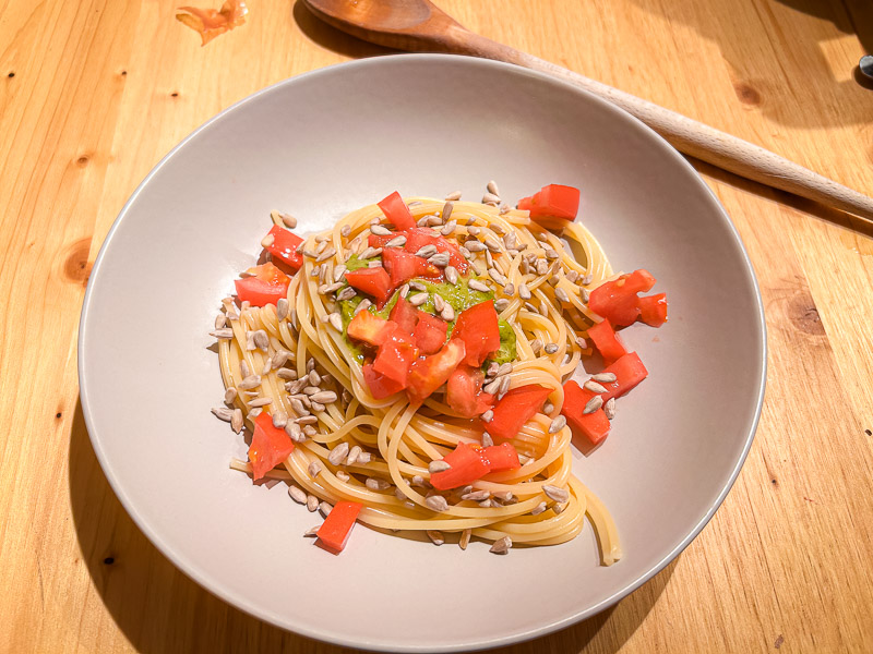 Pasta met tomaten en zonnebloempitten als gezonde koolhydraatbron voor carbo-loading. Een bord spaghetti met verse tomaten en zonnebloempitten, ideaal voor een koolhydraatrijke maaltijd voor een halve marathon.