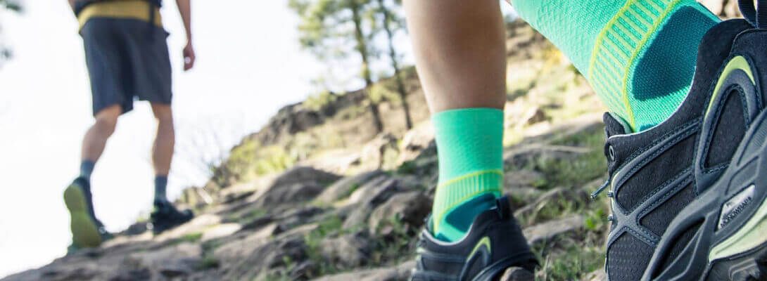 Wandelaars met groene trekking sokken rennen een berg op	 zoom op de sokken