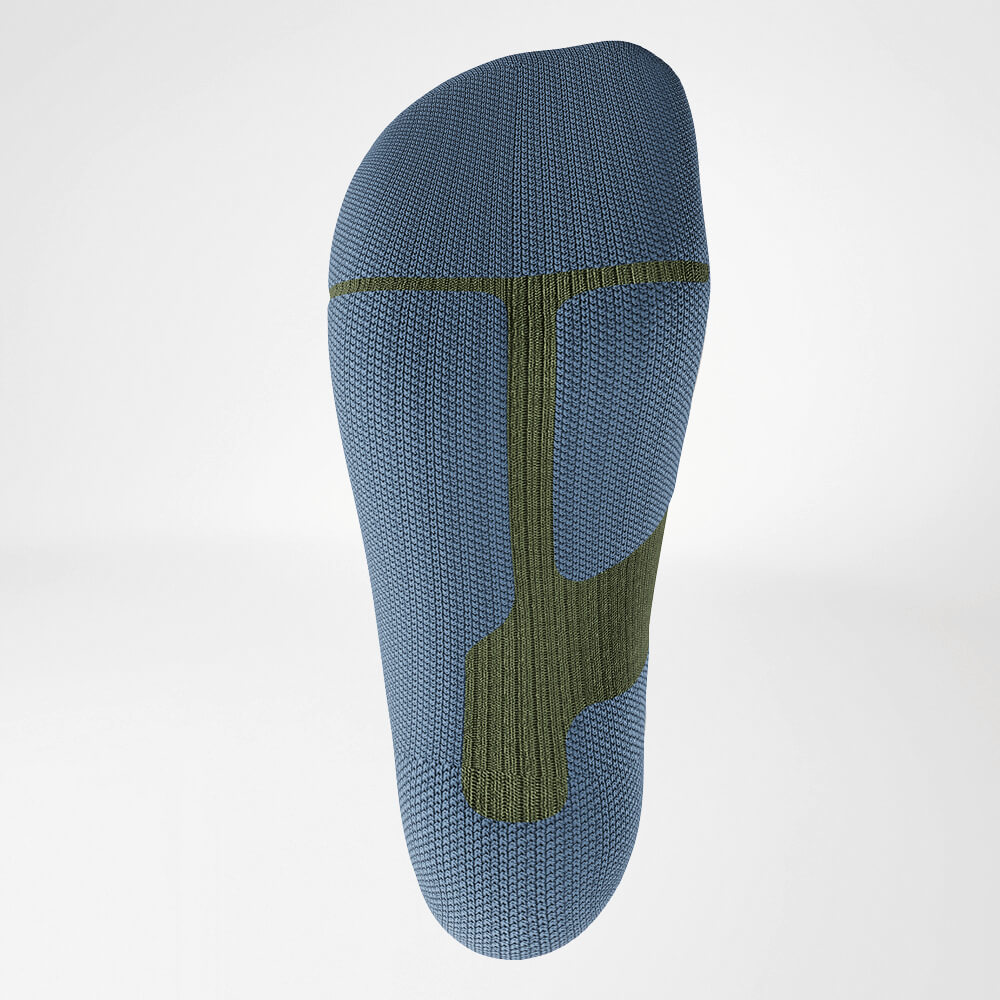 Close-up van de zool van een groene ski-compressiesok met ergonomisch breipatroon voor stabiliteit en demping tijdens intensieve sportactiviteiten.