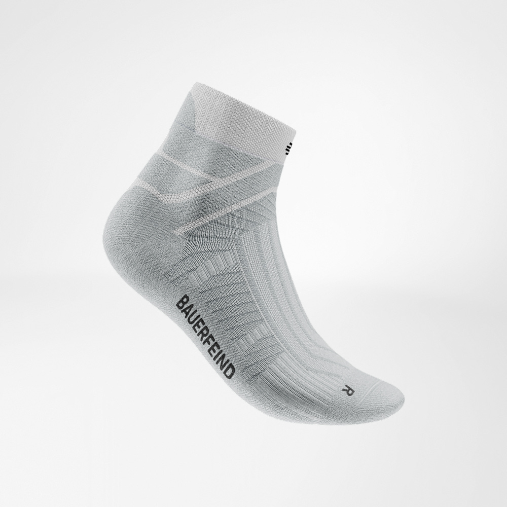 Witte Run Performance Low Cut sok van Bauerfeind in zijaanzicht, met zichtbaar breipatroon, ademende zones en Bauerfeind-logo aan de buitenkant.
