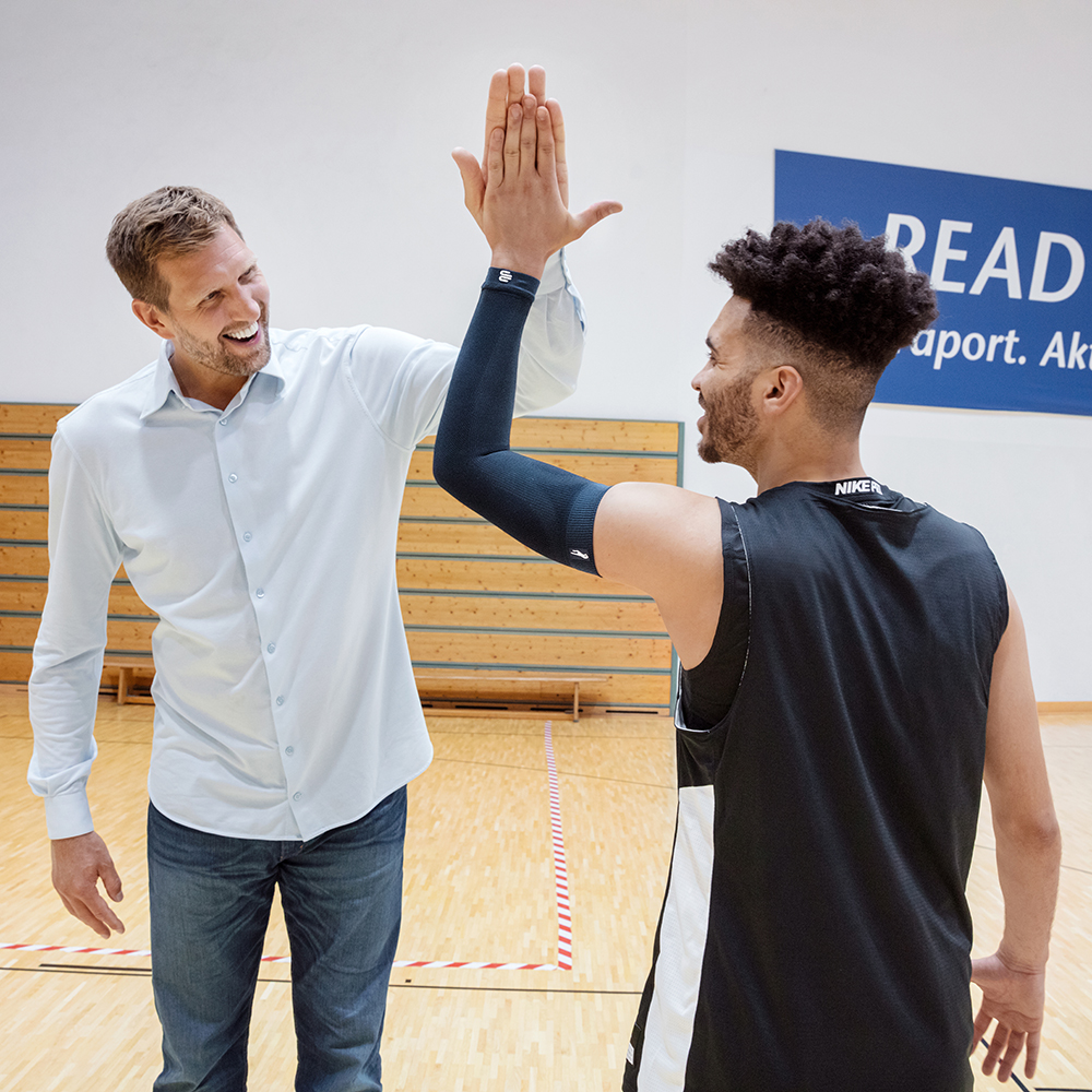 Dirk Nowitzki en een basketbalspeler die de arm mouw van Dirk Nowitzki -editie draagt.