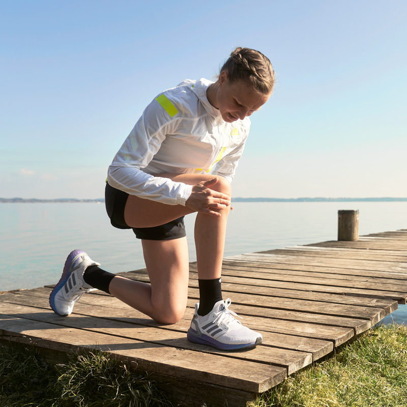 Als je een pijn in je knie voelt, stop dan op het kort en kijk naar Langer Anna Hahner Kniend op de steiger houdt haar knie vast