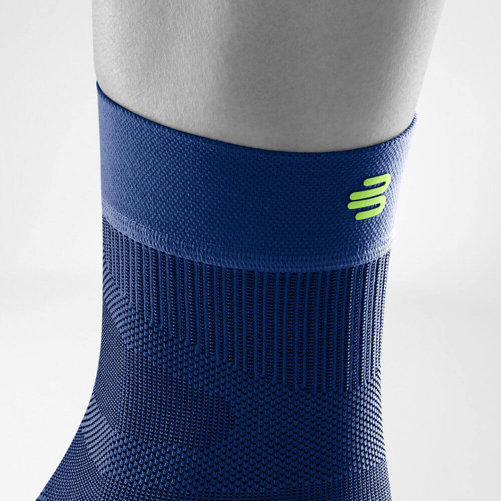 Gedetailleerd uitzicht op het bovenste gebied van de donkerblauwe Sportsleeves voor de enkel inclusief een gebreide curve en logo