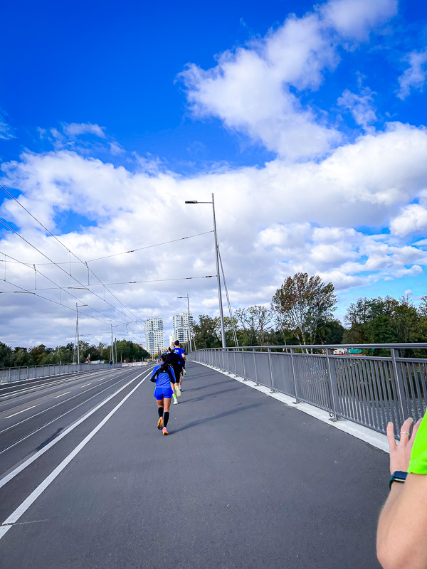Sterke tegenwind en geen beschermende groep bij de halve marathon Hardlopers op een brug vechten tegen een sterke tegenwind zonder de hulp van een beschermende groep tijdens de halve marathon.