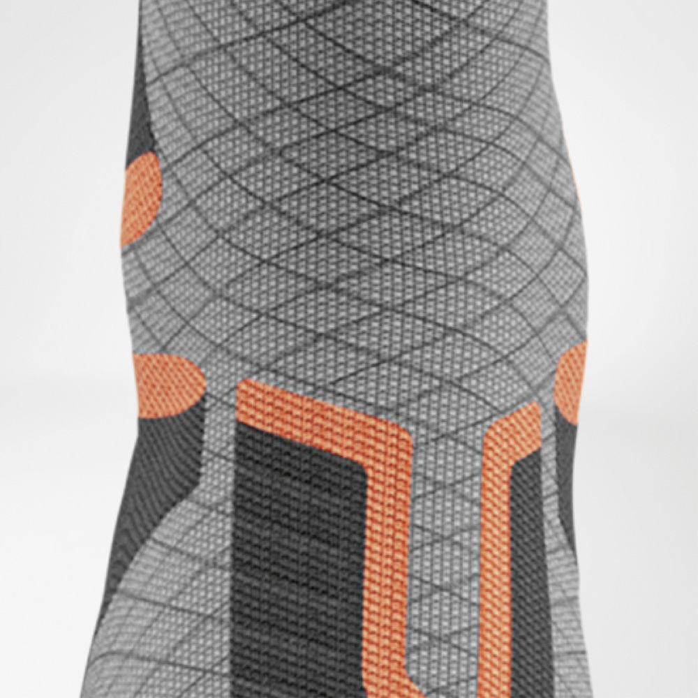 Klaar voor impact – bescherming bij het scheenbeen Close-up aan de voorkant van het scheenbeengedeelte van de ski-compressiekous met oranje U-vormige padding en ruitvormige structuur.