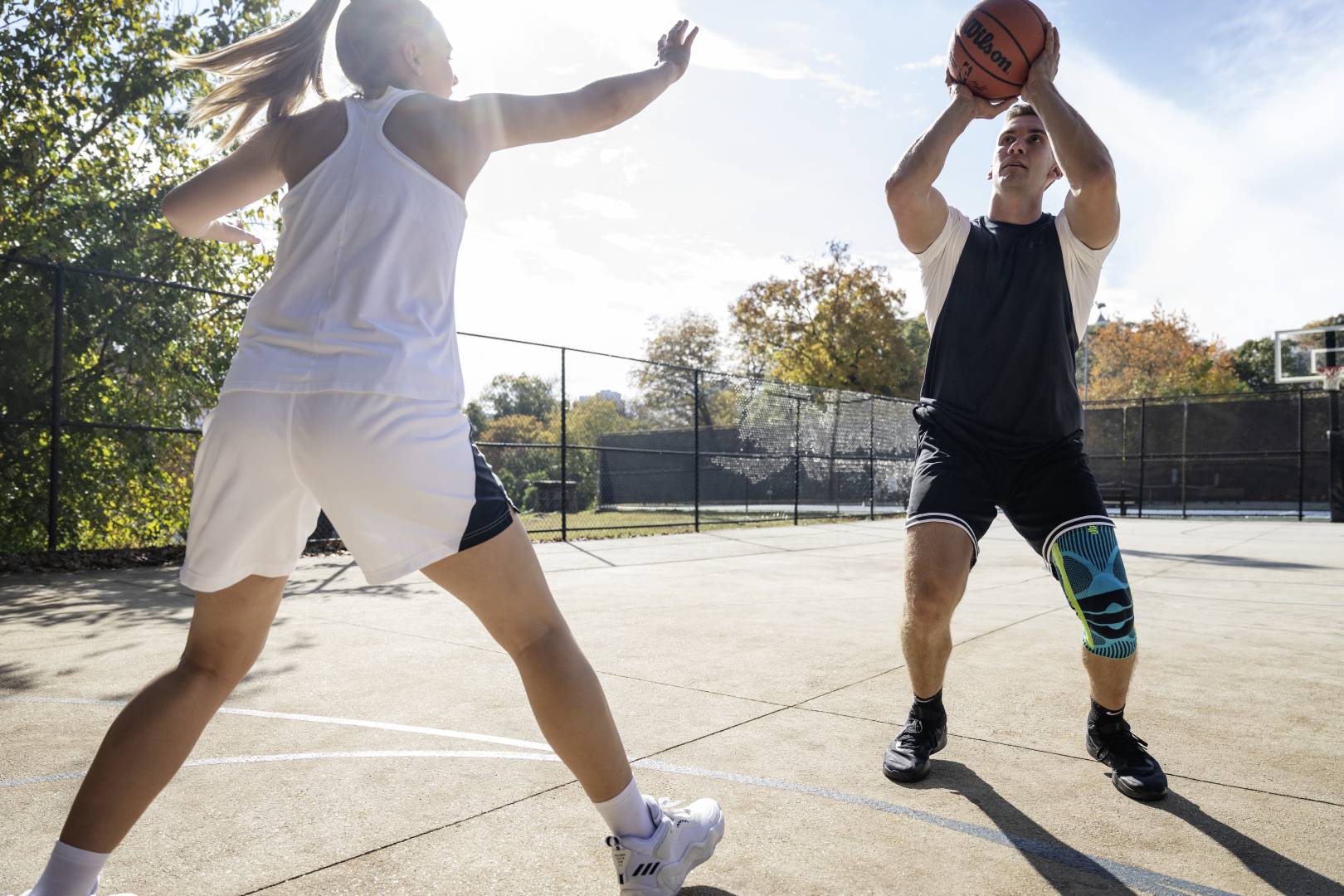 Mensen en stabilisator: onze kniesteun in straatbal Basketbalspelers met een kneeze beginnen met een straatbal terwijl zijn tegenstander hem probeert te blokkeren