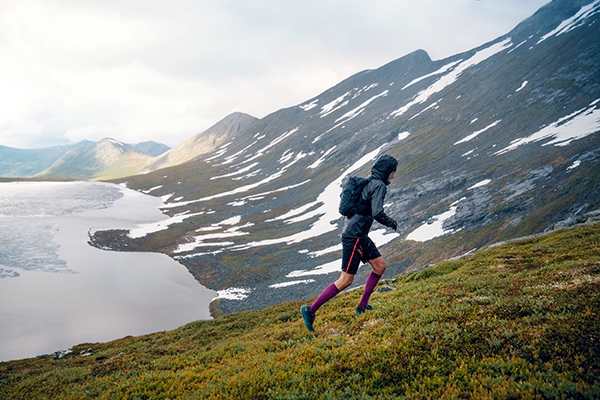 Trailrunner loopt een grasachtige berg omhoog in regenachtig weer