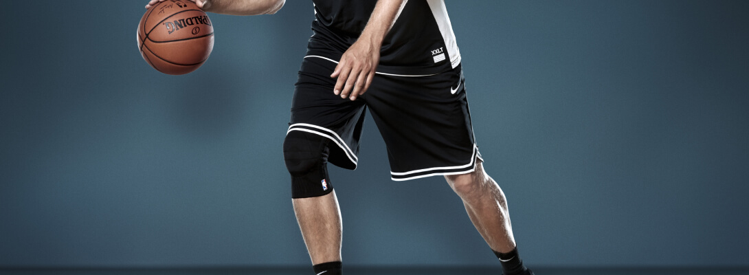 Basketbalspelers tijdens het dribbelen draagt ​​een sportkniesteun Dirk Nowitzki-editie