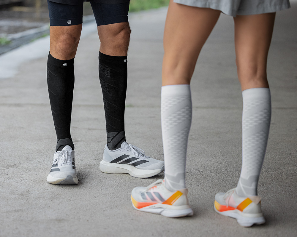 Kikkerperspectief: hardlopers met paarse en witte hardloopsokken lopen door een drukke stad op de achtergrond mensen en lantaarns