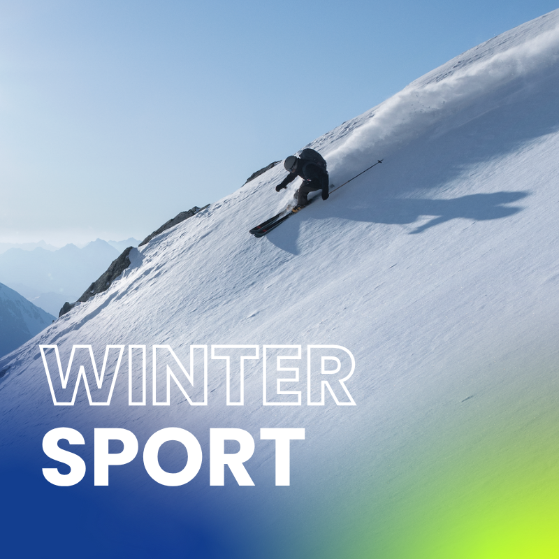 Skiër daalt een steile helling af door verse poedersneeuw en laat een dynamische afdaling zien in alpien terrein bij helder weer.