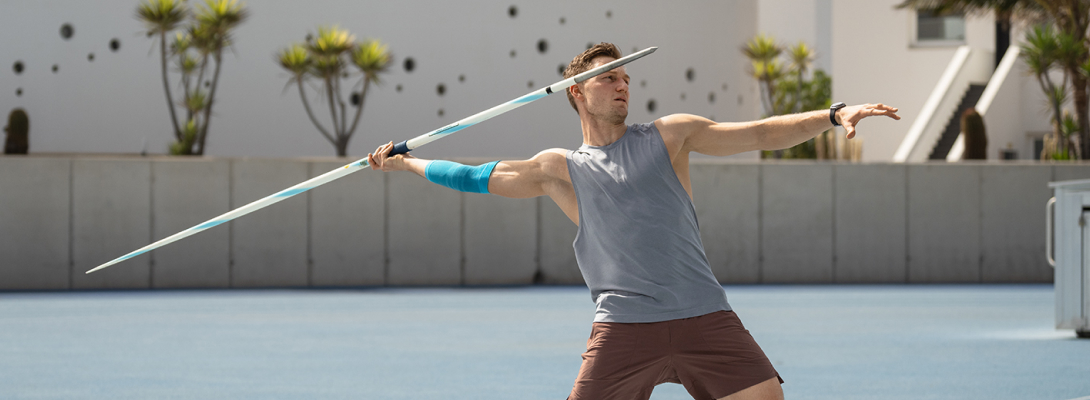 Ellenbogensleeve in de speerworp Man traint de speerworp en draagt een sportleeve voor de elleboog