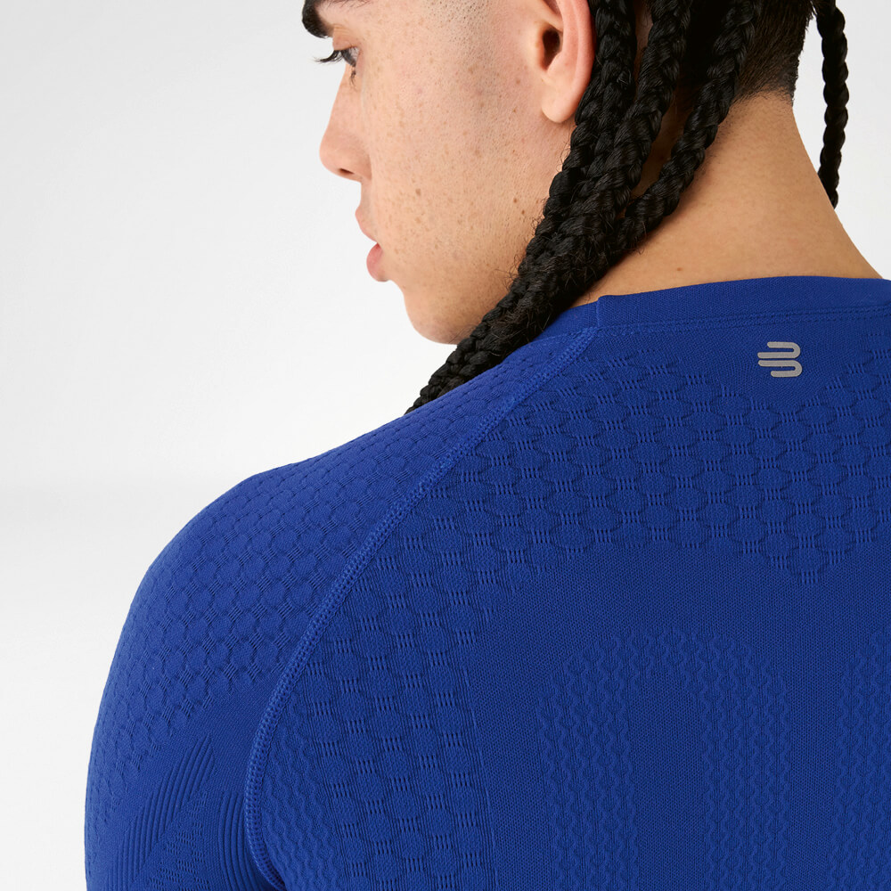 Achteraanzicht van een atleet in een blauw compressieshirt met getextureerde stof en gevlochten haar.