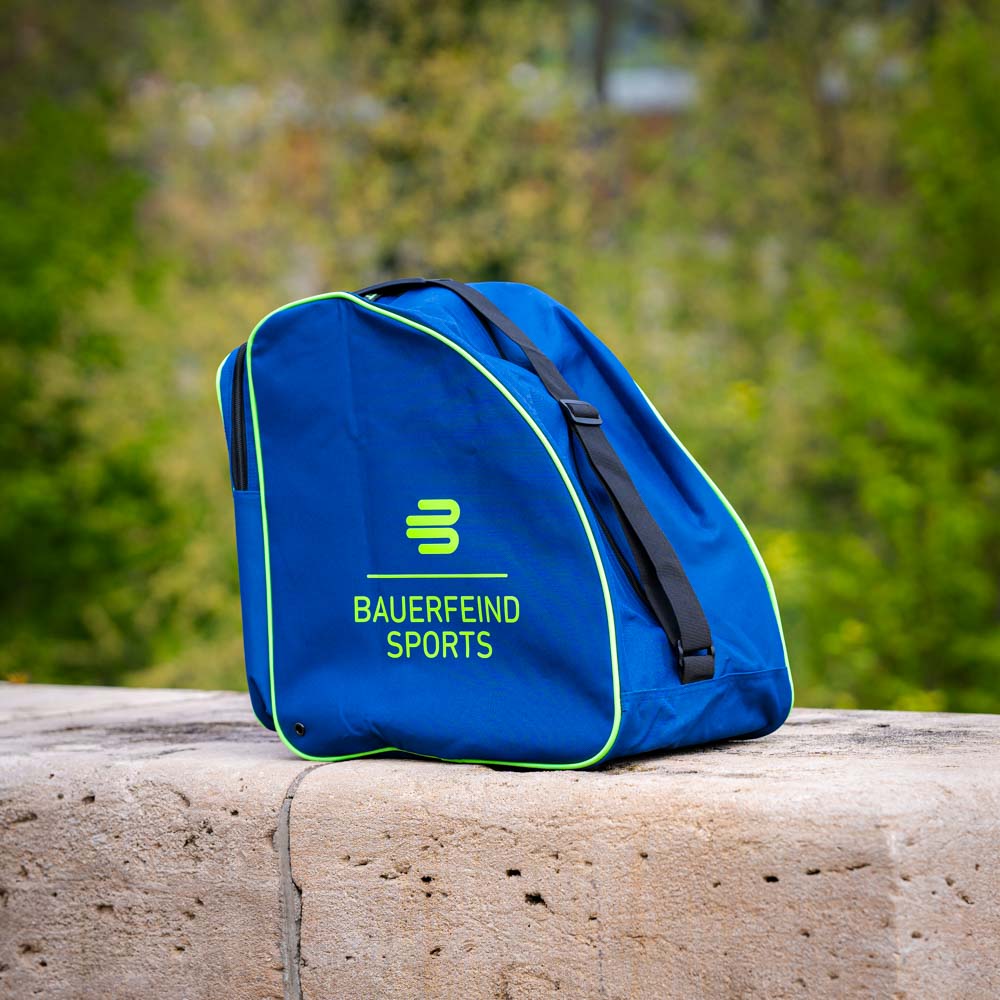 Blauwe Bauerfeind Sports tas op stenen achtergrond Een blauwe tas met het Bauerfeind Sports logo, gefotografeerd buiten op een stenen achtergrond. De tas heeft groene accenten en zwarte riemen.