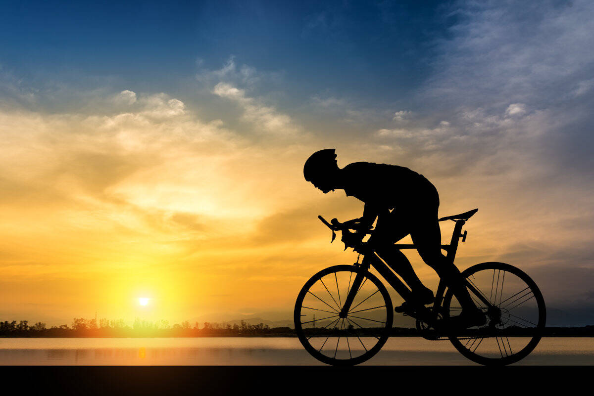 Silhouet van een fietser in de schaduw bij zonsondergang