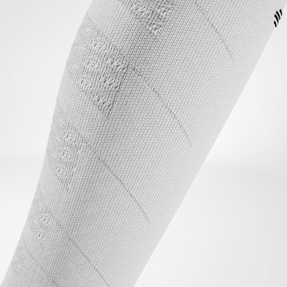 Detailopname van een witte compressiesleeve met opvallende breistructuur. Helder design met ondersteuning en kracht.