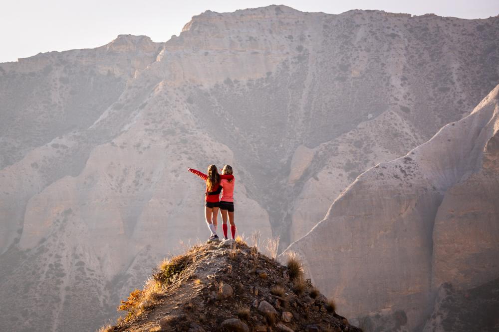 Twee vrouwen juichen een bergtop toe