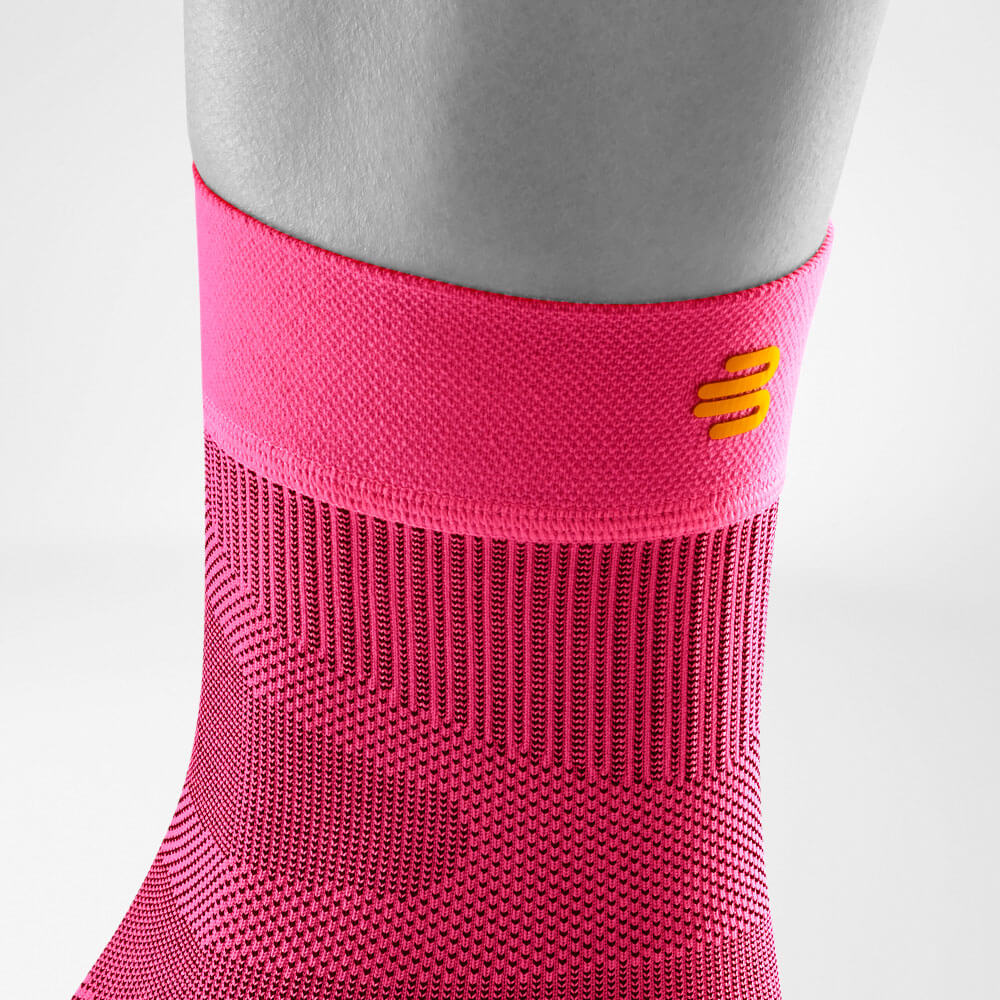 Detailansicht des oberen Bereiches des pink-farbenen Sportsleeves für das Sprunggelenk inklusive Gestrickverlauf und Logo