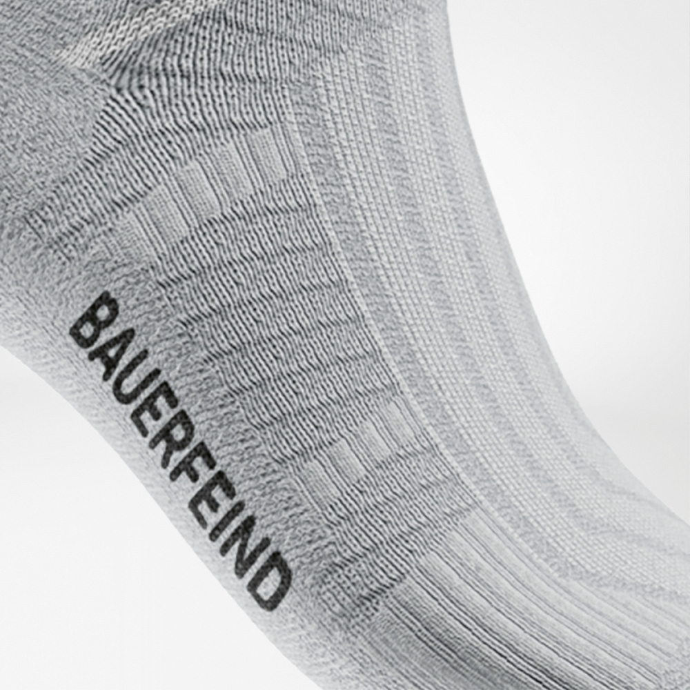 Close-up van een witte midcut hardloopsok van Bauerfeind met ribbelstructuur en ingebreide steunzone bij de voetboog. De ademende, naadloze afwerking garandeert comfort en stabiliteit tijdens het hardlopen.
