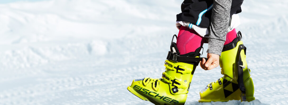 Beeldsluiting toont een persoon in ski -laarzen met ski -sokken eronder dat ze de sluiting van de laarzen bereikt