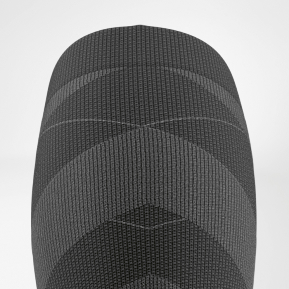 Close-up van de bovenste boord van de ski-performance sok in zwart en grijs met een fijne ribstructuur voor optimale grip op het onderbeen.