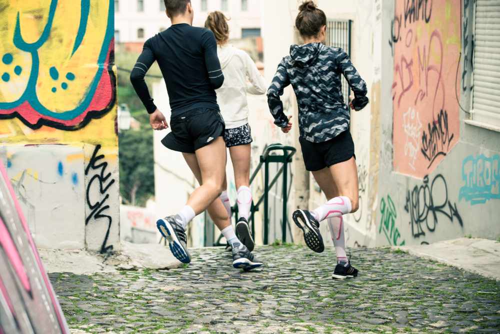 Groep van drie lopers loopt om een ​​hoek in een oude stad met graffiti op de muren op een trap