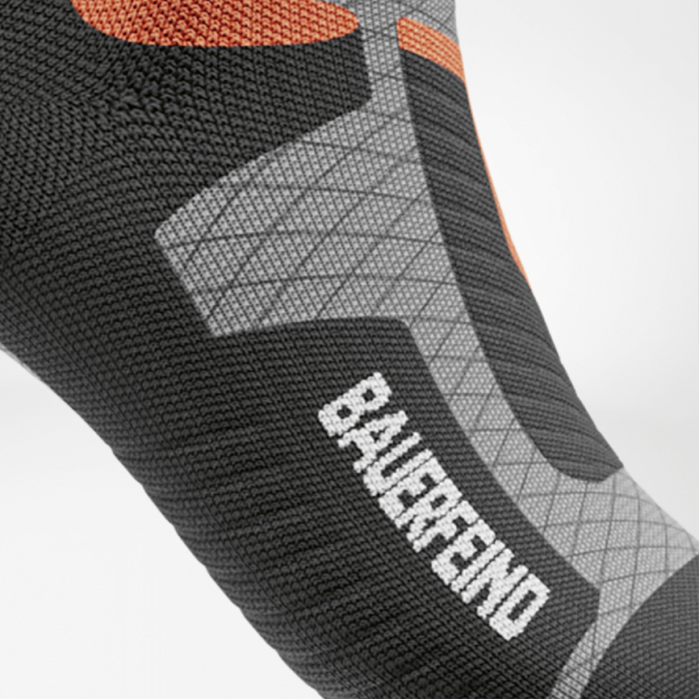 Zichtbare performance – BAUERFEIND-ondersteuning bij elke stap Detail van de zijkant van de voet van de ski-compressiekous voor dames met duidelijk zichtbaar BAUERFEIND-logo en ergonomische structuur.
